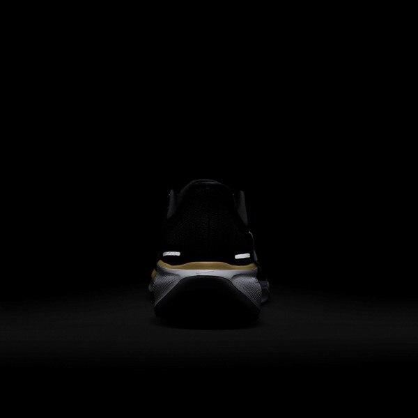 Rear view of black Nike running shoe in low-light, showing reflective heel details and white outsole trim